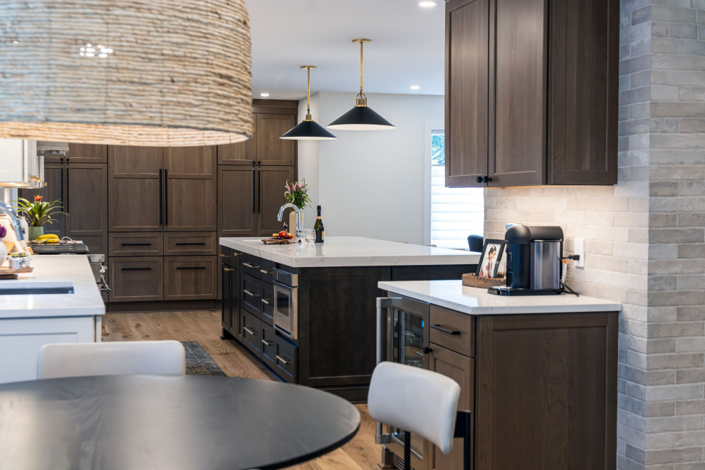 Example of a mid-sized transitional medium tone wood floor kitchen design in DC Metro with a single-bowl sink, flat-panel cabinets, quartz countertops, white backsplash, quartz backsplash, stainless steel appliances, an island and white countertops