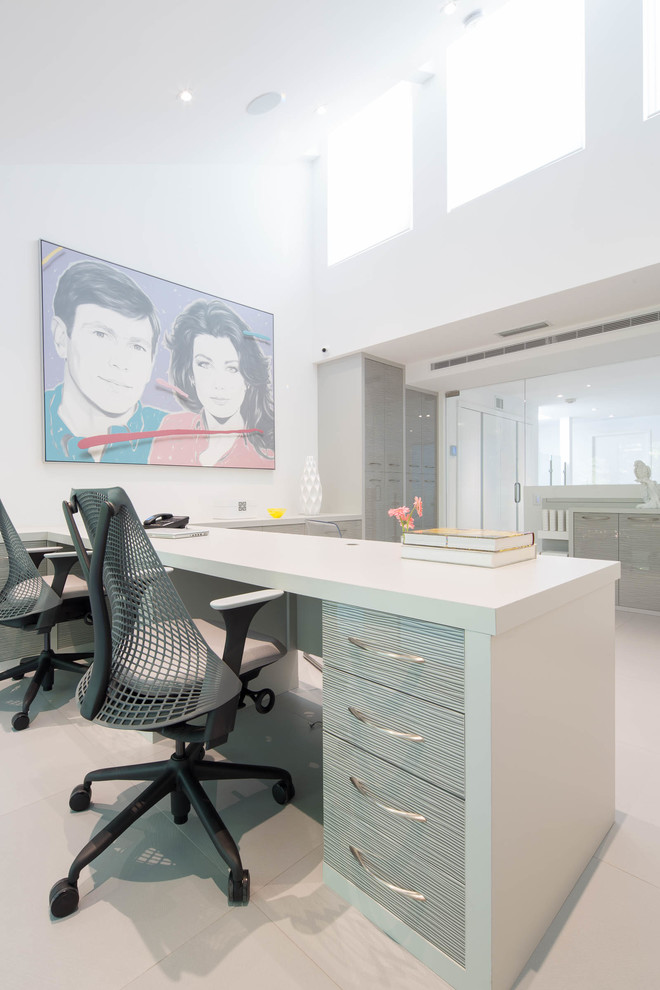 This is an example of a large modern home office in Miami with white walls, porcelain floors and a built-in desk.