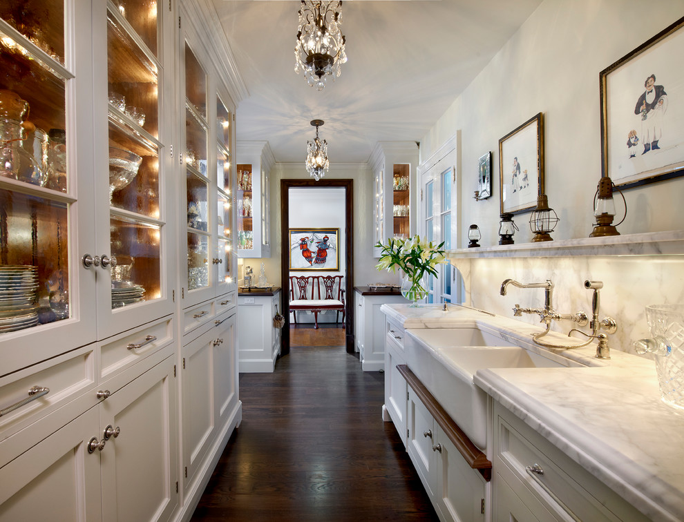 Traditional galley kitchen pantry in Chicago with recessed-panel cabinets, white cabinets, marble benchtops, white splashback, marble splashback, with island, brown floor, white benchtop, a farmhouse sink and dark hardwood floors.