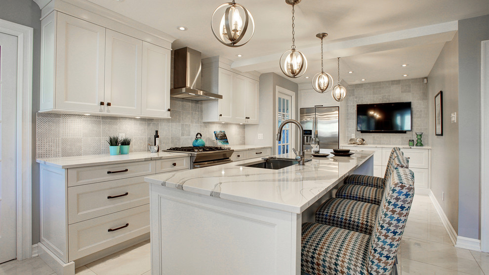 Mid-sized transitional l-shaped beige floor enclosed kitchen photo in Montreal with a drop-in sink, shaker cabinets, white cabinets, gray backsplash, stainless steel appliances, an island and white countertops