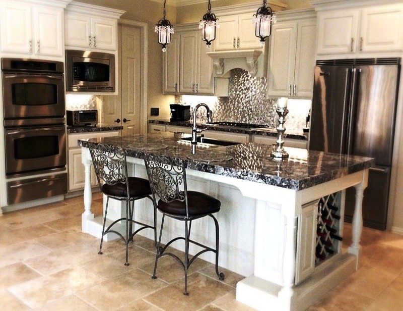 Eat-in kitchen - mid-sized transitional l-shaped travertine floor eat-in kitchen idea in Houston with a farmhouse sink, raised-panel cabinets, white cabinets, granite countertops, metallic backsplash, metal backsplash, stainless steel appliances and an island