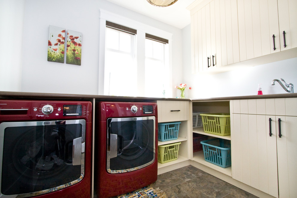Inspiration for a mid-sized country l-shaped dedicated laundry room in Vancouver with flat-panel cabinets, beige cabinets, grey walls, a side-by-side washer and dryer and brown floor.
