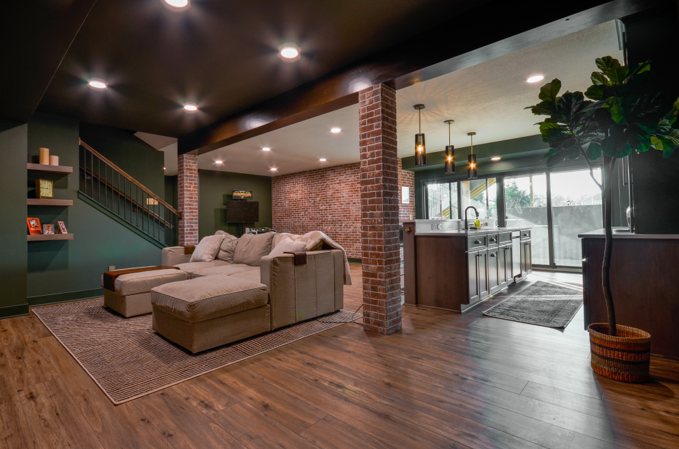 Cette image montre un grand sous-sol minimaliste donnant sur l'extérieur avec un bar de salon, un mur vert, un sol en vinyl, poutres apparentes et un mur en parement de brique.