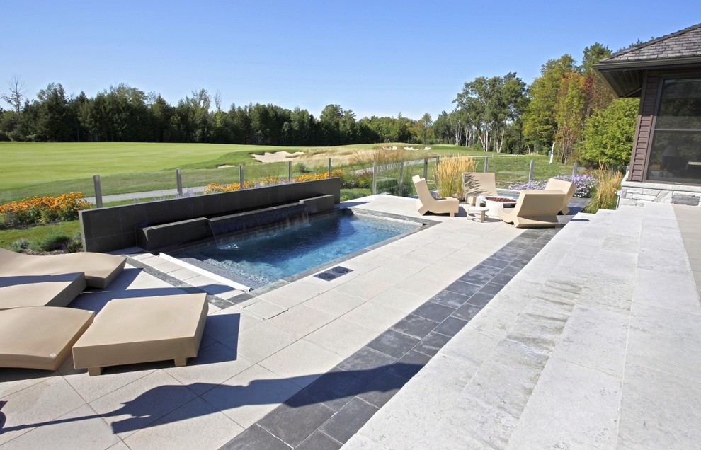 Design ideas for a small contemporary backyard custom-shaped lap pool in Toronto with a hot tub and natural stone pavers.