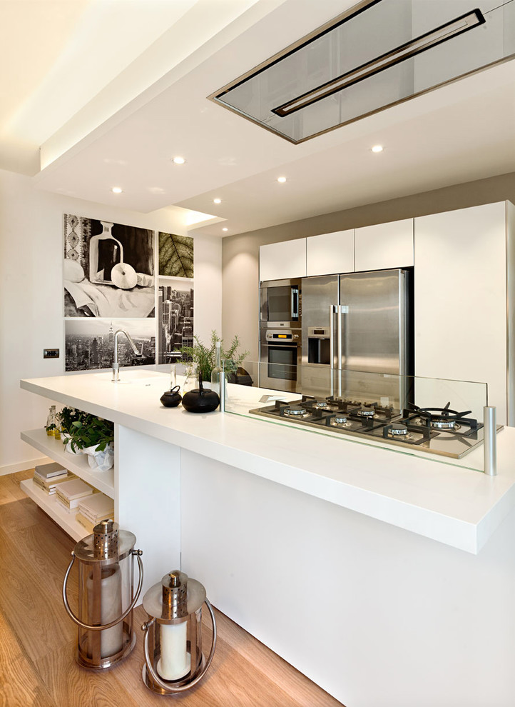 Design ideas for a mid-sized contemporary single-wall open plan kitchen in Other with flat-panel cabinets, white cabinets, quartz benchtops, window splashback, stainless steel appliances, medium hardwood floors, with island and brown floor.