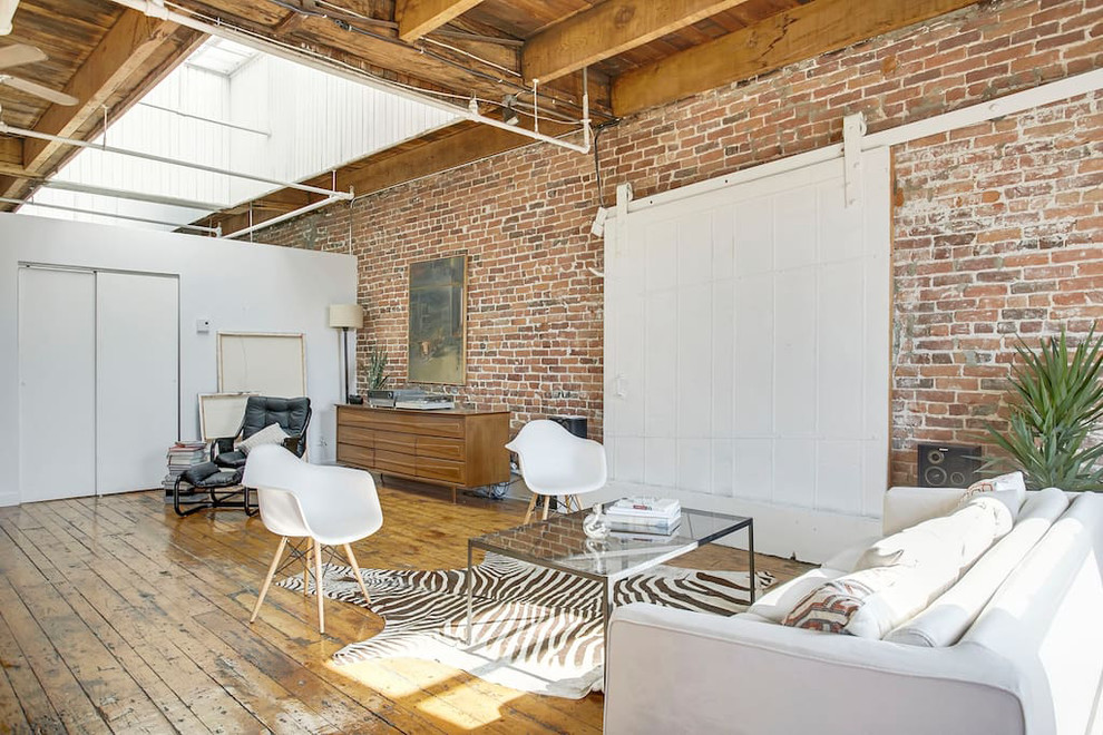 Photo of a large industrial loft-style living room in New York with medium hardwood floors, no fireplace, no tv, brown floor and beige walls.