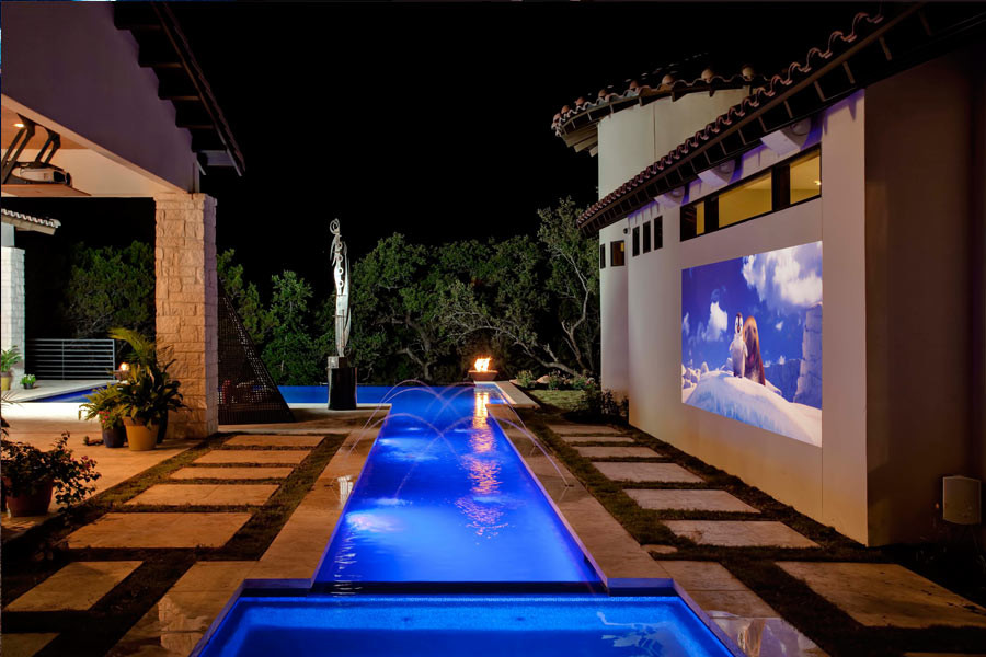 Inspiration for a large traditional backyard l-shaped lap pool in Austin with a water feature and concrete slab.