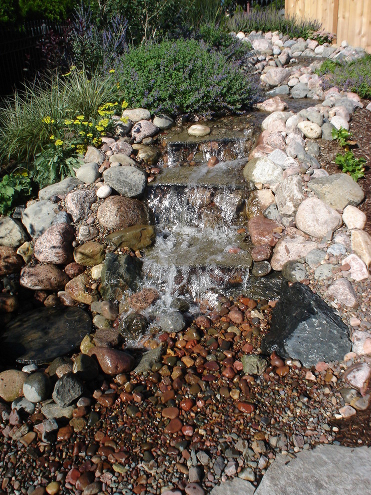 Design ideas for a mid-sized transitional full sun backyard stone landscaping in Chicago for spring.