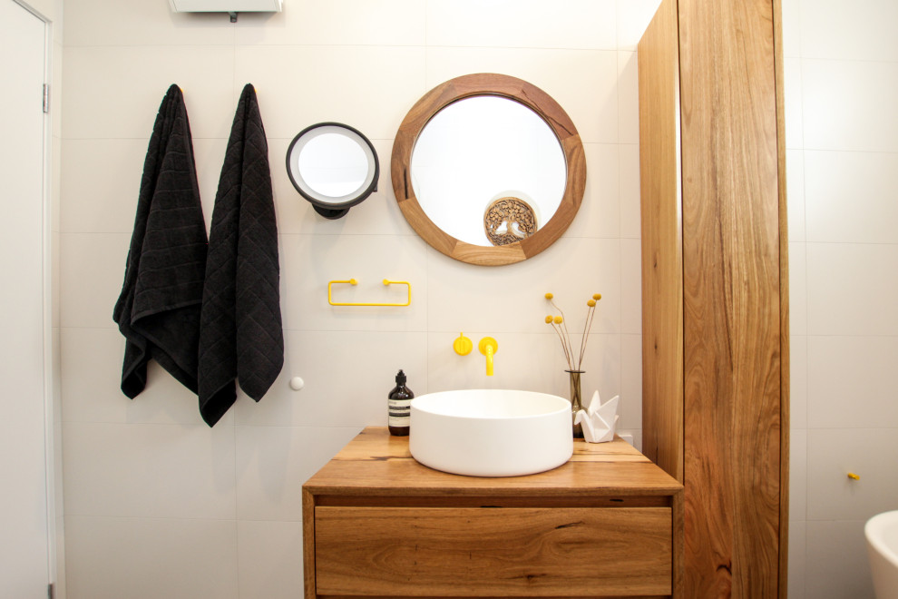 Mid-sized eclectic master bathroom in Sydney with medium wood cabinets, a freestanding tub, a corner shower, a two-piece toilet, white tile, white walls, a vessel sink, grey floor, a hinged shower door, a niche, a single vanity and a floating vanity.