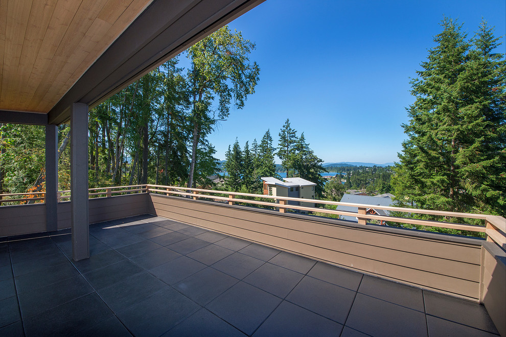 Example of a large transitional backyard balcony deck design in Seattle with a roof extension