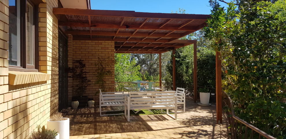 Small midcentury courtyard patio in Canberra - Queanbeyan with tile and a pergola.