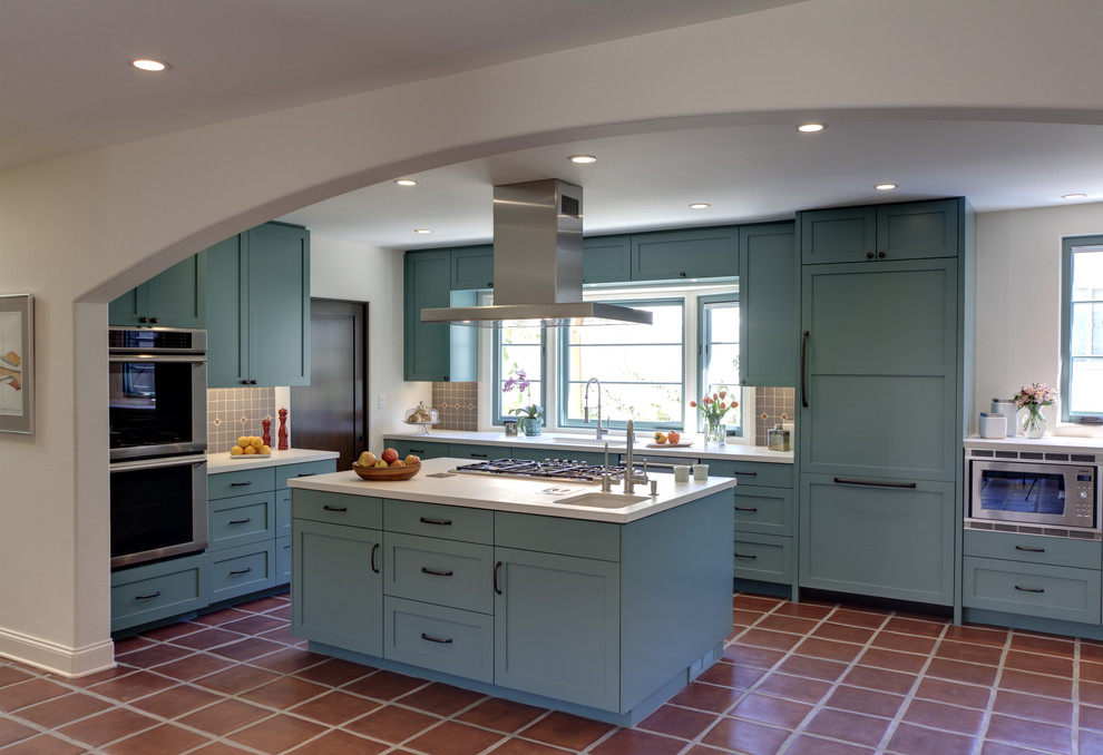 This is an example of a mid-sized mediterranean u-shaped kitchen in Los Angeles with a single-bowl sink, shaker cabinets, blue cabinets, grey splashback, stainless steel appliances, terra-cotta floors and with island.