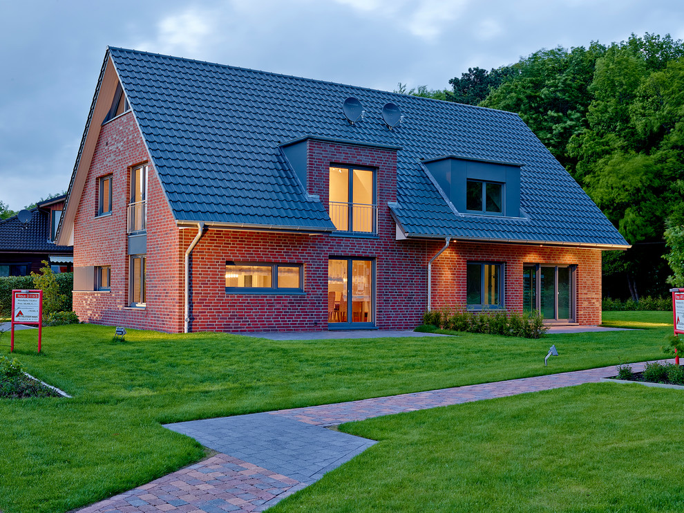 This is an example of a mid-sized country one-storey brick duplex exterior in Hamburg with a tile roof and a gable roof.