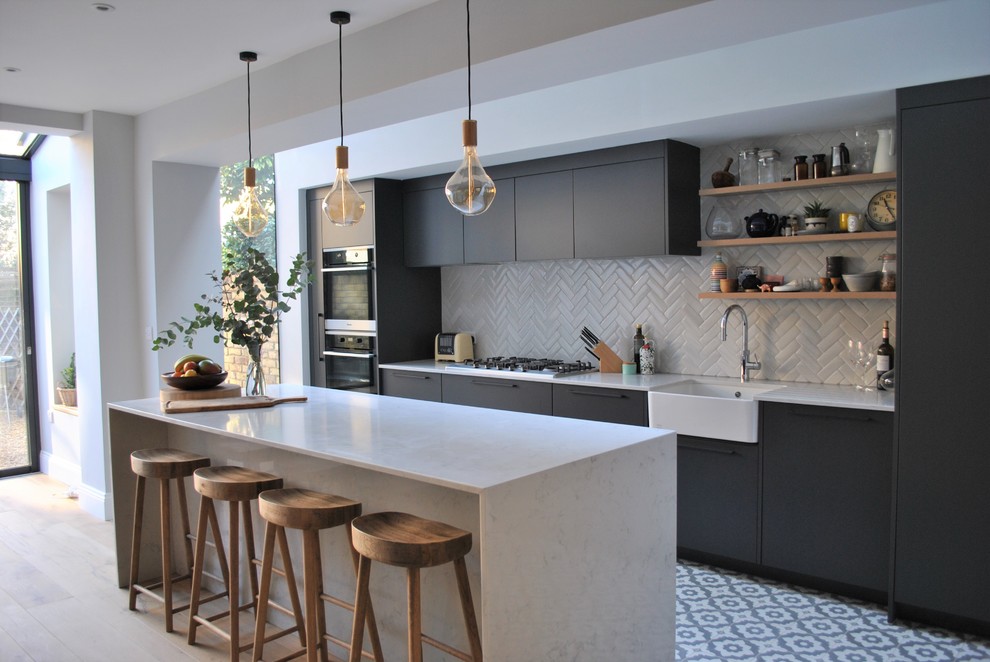 Contemporary eat-in kitchen in London with a farmhouse sink, flat-panel cabinets, grey cabinets, quartzite benchtops, white splashback, subway tile splashback, ceramic floors and multi-coloured floor.