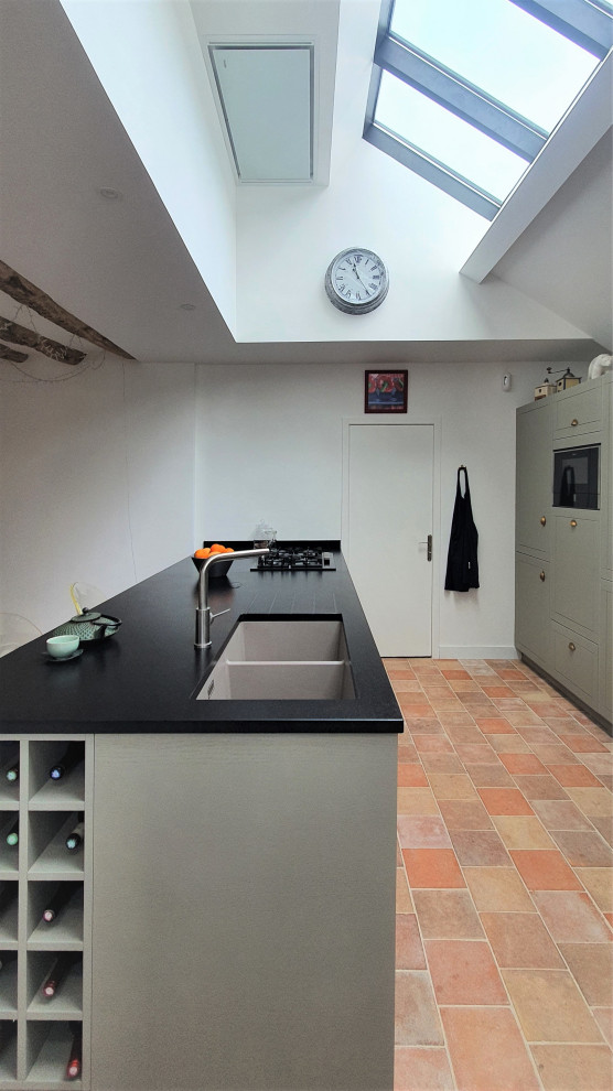 Design ideas for an expansive midcentury galley open plan kitchen in Other with an integrated sink, flat-panel cabinets, green cabinets, granite benchtops, black splashback, granite splashback, panelled appliances, cement tiles, with island, pink floor and black benchtop.