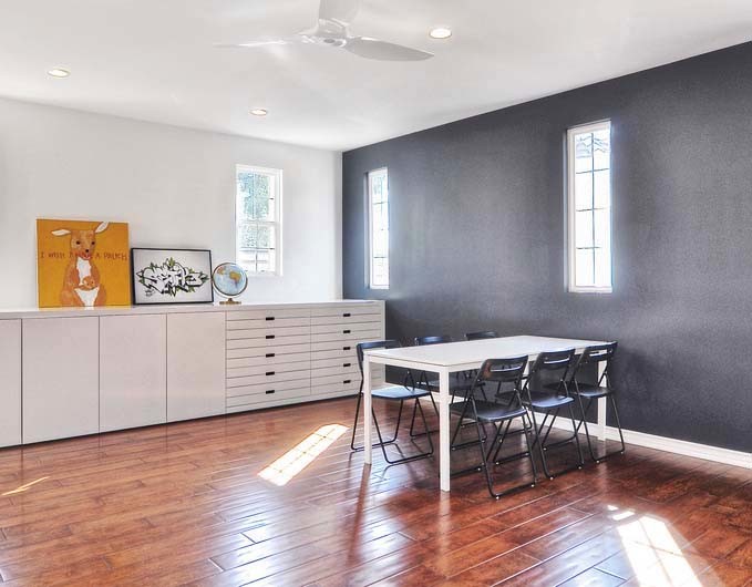 Inspiration for an expansive modern craft room in Orange County with medium hardwood floors, no fireplace, a freestanding desk and grey walls.