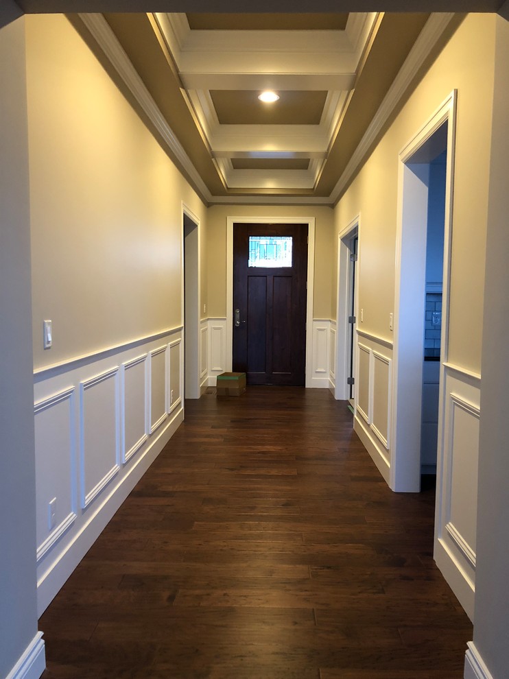 This is an example of a mid-sized transitional entryway in Other with beige walls, dark hardwood floors, a dark wood front door and brown floor.