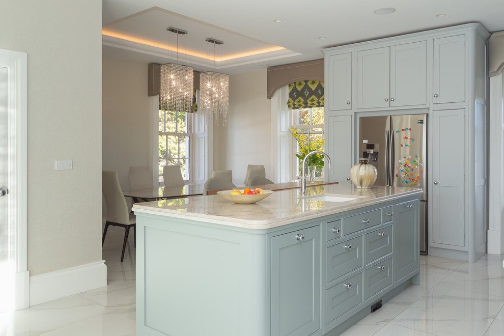 Photo of a transitional eat-in kitchen in Belfast with an undermount sink, shaker cabinets, blue cabinets, stainless steel appliances, marble floors, with island, white floor and beige benchtop.