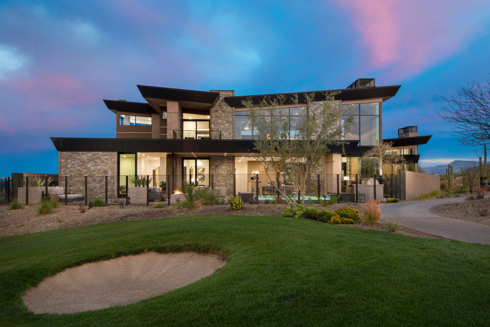 Expansive modern three-storey house exterior in Phoenix with stone veneer and a butterfly roof.