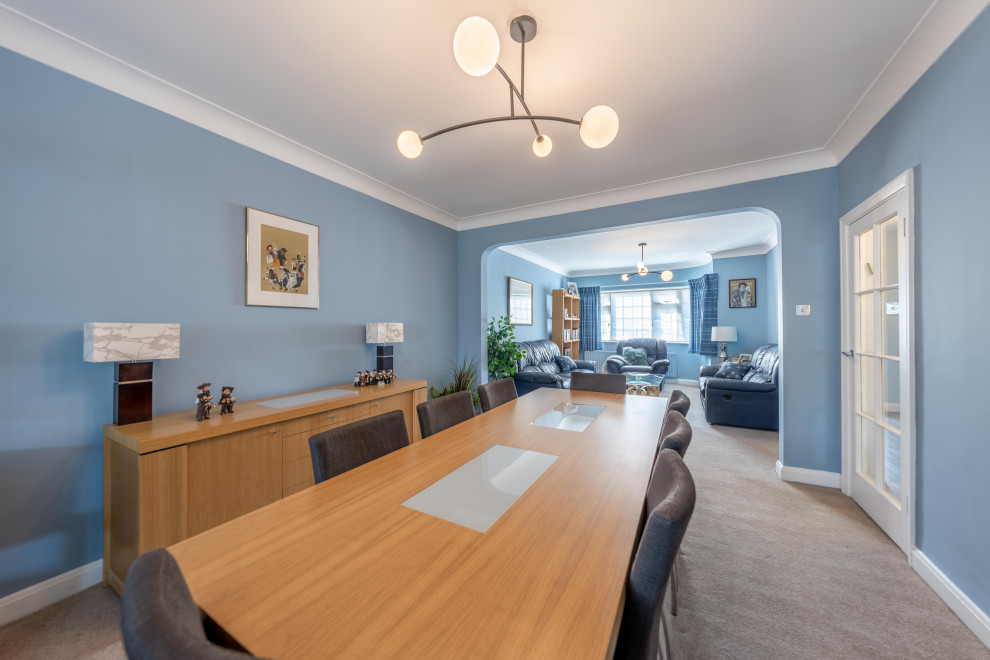 Immagine di una grande sala da pranzo aperta verso il soggiorno minimalista con pareti blu, moquette e pavimento marrone