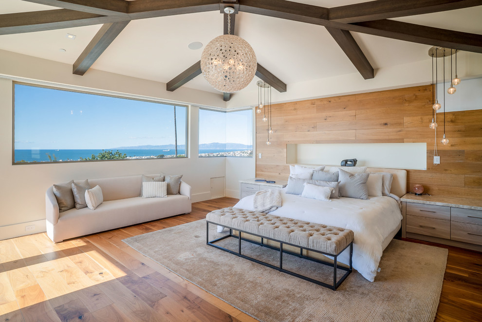 This is an example of a large contemporary master bedroom in Los Angeles with medium hardwood floors, a standard fireplace, a stone fireplace surround, brown floor and brown walls.