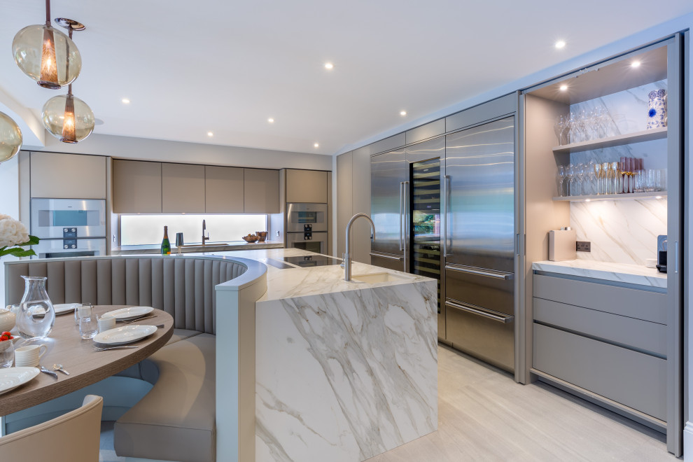 Photo of a large contemporary l-shaped open plan kitchen in Cheshire with flat-panel cabinets, grey cabinets, tile benchtops, with island, white benchtop, an undermount sink, multi-coloured splashback, marble splashback, stainless steel appliances, light hardwood floors and beige floor.