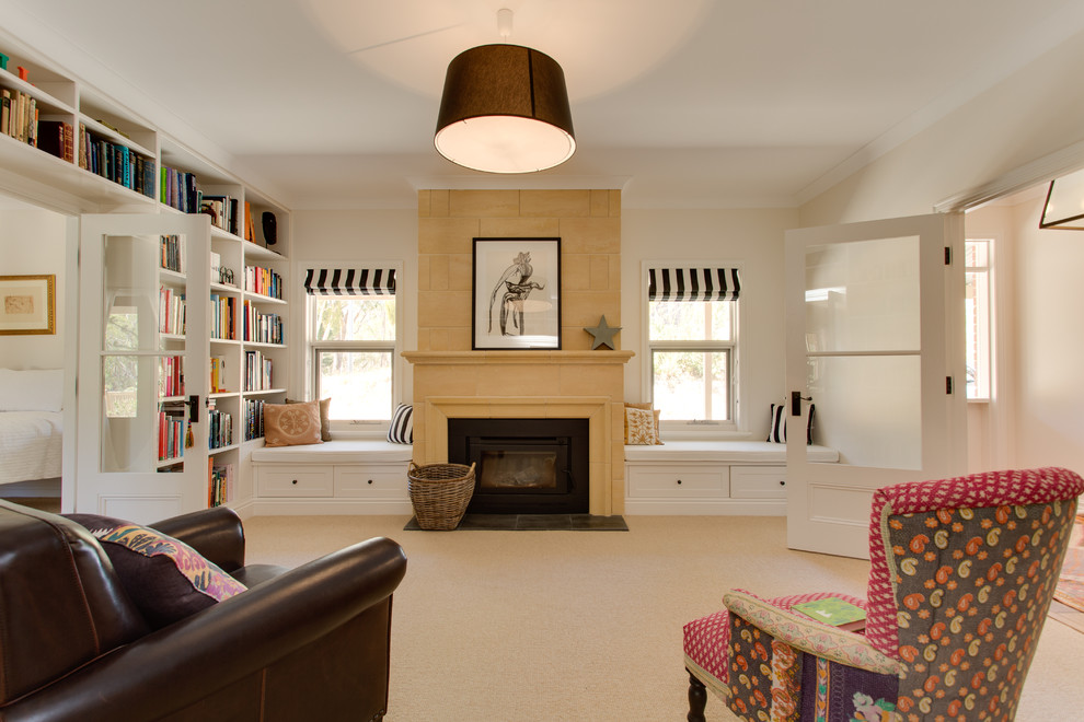 Photo of a mid-sized traditional enclosed living room in Adelaide with a library, white walls, carpet, a wood stove, a stone fireplace surround and no tv.