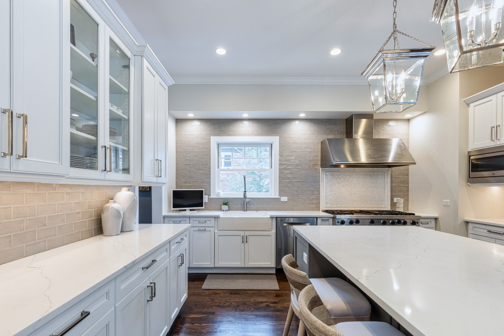 Inspiration for a large transitional u-shaped dark wood floor and brown floor eat-in kitchen remodel in Chicago with a farmhouse sink, beaded inset cabinets, white cabinets, quartz countertops, gray backsplash, glass tile backsplash, stainless steel appliances, an island and white countertops