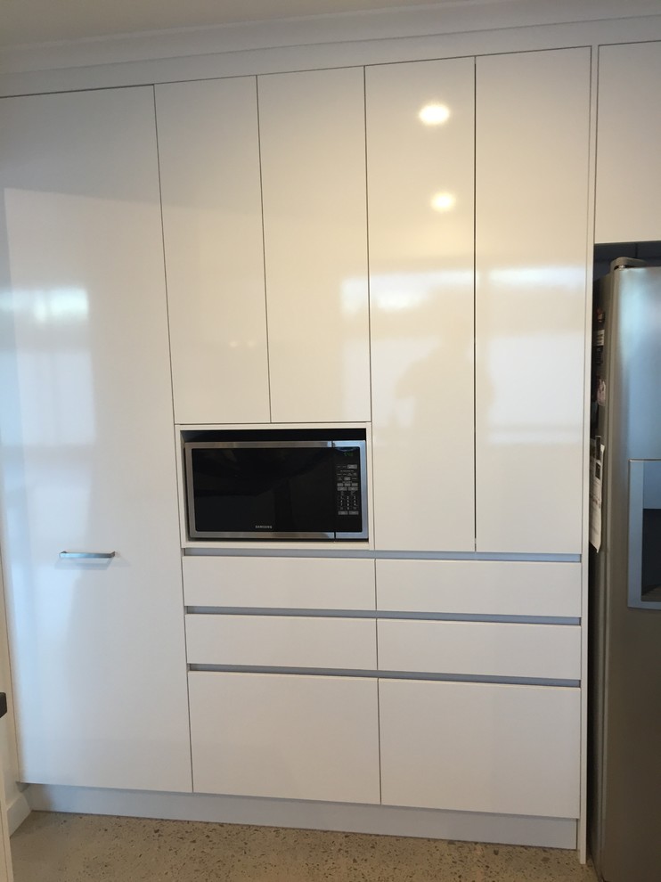 This is an example of a large modern u-shaped kitchen pantry in Sunshine Coast with an undermount sink, open cabinets, white cabinets, quartz benchtops, grey splashback, ceramic splashback, stainless steel appliances, concrete floors and no island.