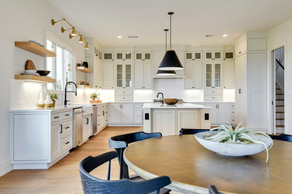 Design ideas for a large transitional u-shaped eat-in kitchen in Austin with a farmhouse sink, recessed-panel cabinets, white cabinets, white splashback, ceramic splashback, stainless steel appliances, medium hardwood floors, with island, beige floor, white benchtop and quartz benchtops.