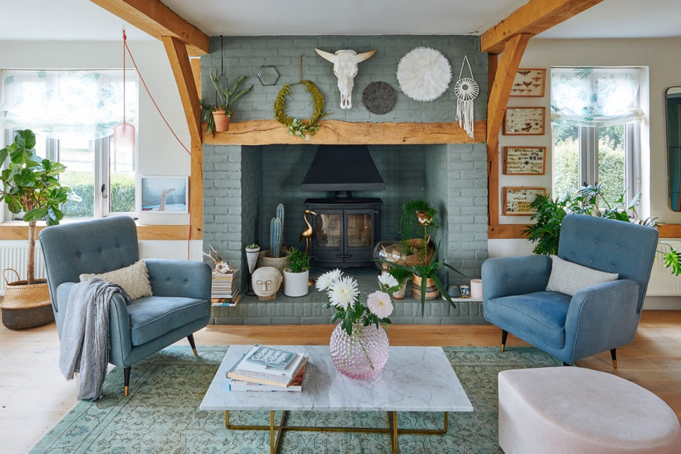 Inspiration for a large country formal enclosed living room in Hampshire with white walls, medium hardwood floors, a wood stove, a brick fireplace surround, no tv, brown floor, exposed beam and brick walls.