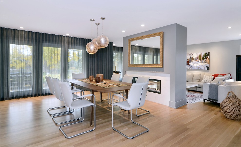Inspiration for a contemporary open plan dining in Calgary with grey walls, light hardwood floors, a tile fireplace surround and a two-sided fireplace.