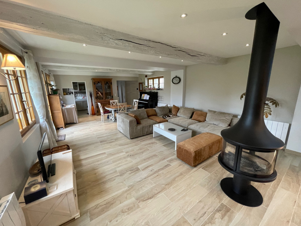 Geräumiges Country Wohnzimmer mit beiger Wandfarbe, Keramikboden, Kaminofen und beigem Boden in Le Havre