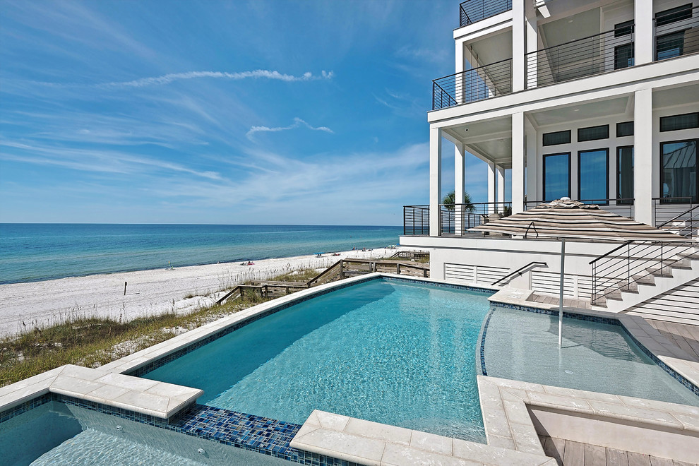 Photo of an expansive beach style backyard custom-shaped pool in Miami with a hot tub and decking.
