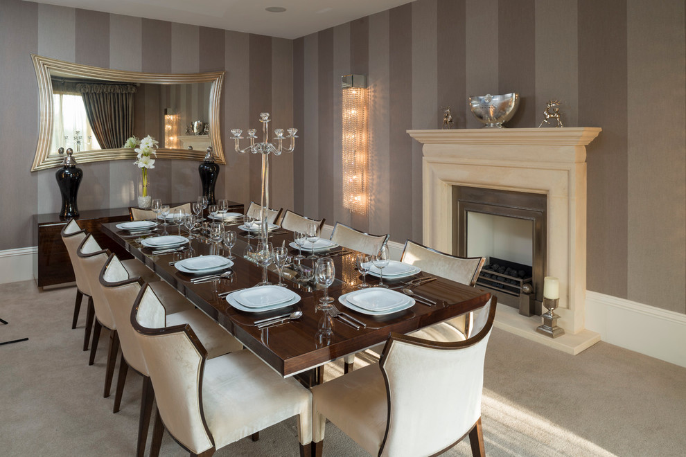Photo of a mid-sized transitional separate dining room in West Midlands with beige walls, carpet, a standard fireplace and a stone fireplace surround.