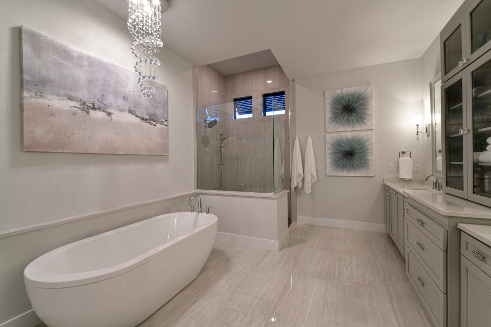 Freestanding bathtub - mid-sized transitional master gray tile and porcelain tile porcelain tile, white floor and double-sink freestanding bathtub idea with shaker cabinets, gray cabinets, a two-piece toilet, gray walls, an undermount sink, quartz countertops, white countertops and a built-in vanity