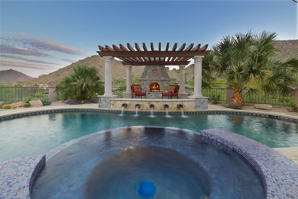 Inspiration for a large mediterranean backyard custom-shaped natural pool in Phoenix with a hot tub and concrete pavers.