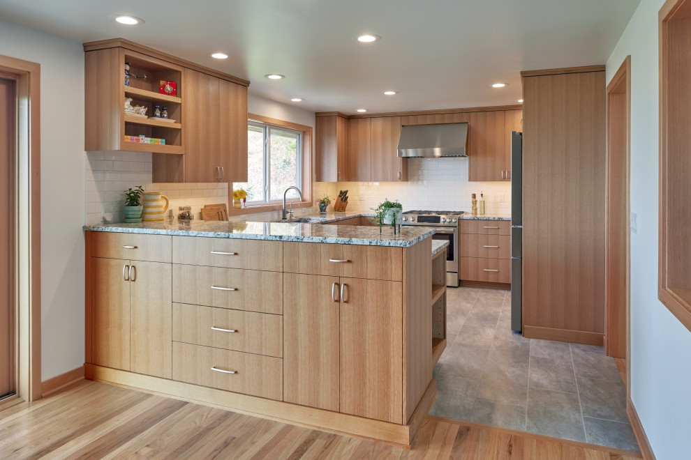 Inspiration for a mid-sized midcentury u-shaped eat-in kitchen in Seattle with a double-bowl sink, flat-panel cabinets, light wood cabinets, granite benchtops, white splashback, ceramic splashback, stainless steel appliances, porcelain floors, a peninsula, grey floor and multi-coloured benchtop.