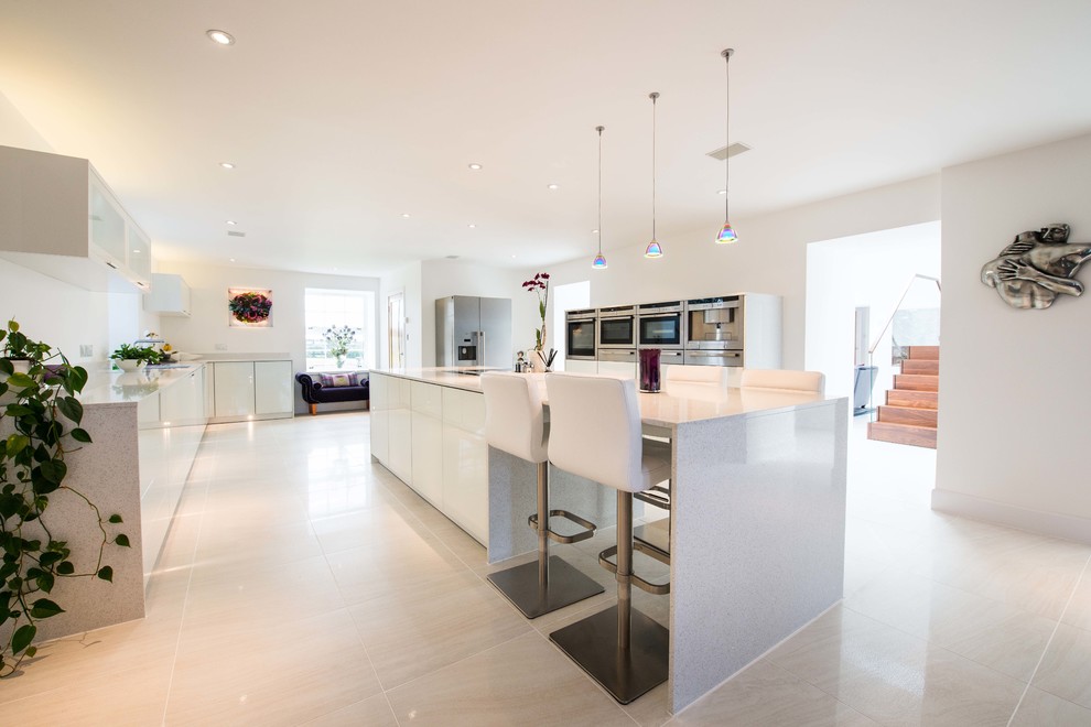 Large modern eat-in kitchen in Other with a double-bowl sink, glass-front cabinets, white cabinets, quartzite benchtops, porcelain splashback, stainless steel appliances, porcelain floors and with island.
