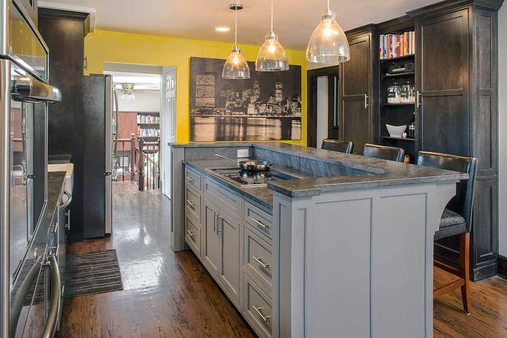 Inspiration for a mid-sized transitional galley medium tone wood floor eat-in kitchen remodel with a farmhouse sink, beaded inset cabinets, dark wood cabinets, granite countertops, beige backsplash, ceramic backsplash, stainless steel appliances, multicolored walls and an island