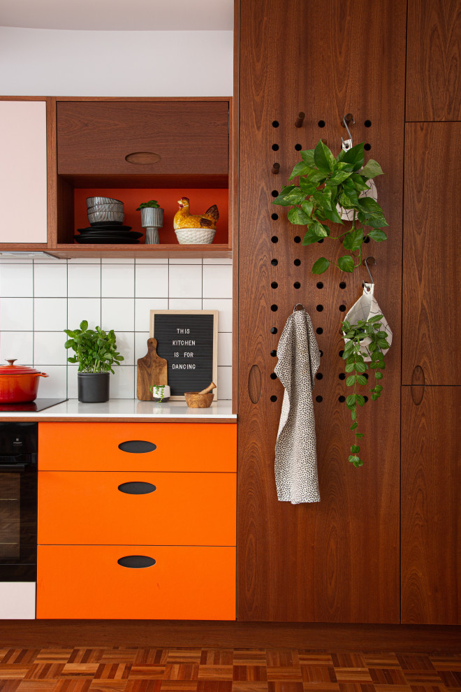 Immagine di una cucina moderna di medie dimensioni con ante lisce, top in superficie solida, paraspruzzi bianco, paraspruzzi con piastrelle in ceramica, parquet scuro, top bianco e ante arancioni
