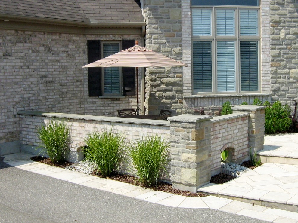 This is an example of a large contemporary courtyard full sun driveway for summer in Toronto with natural stone pavers.