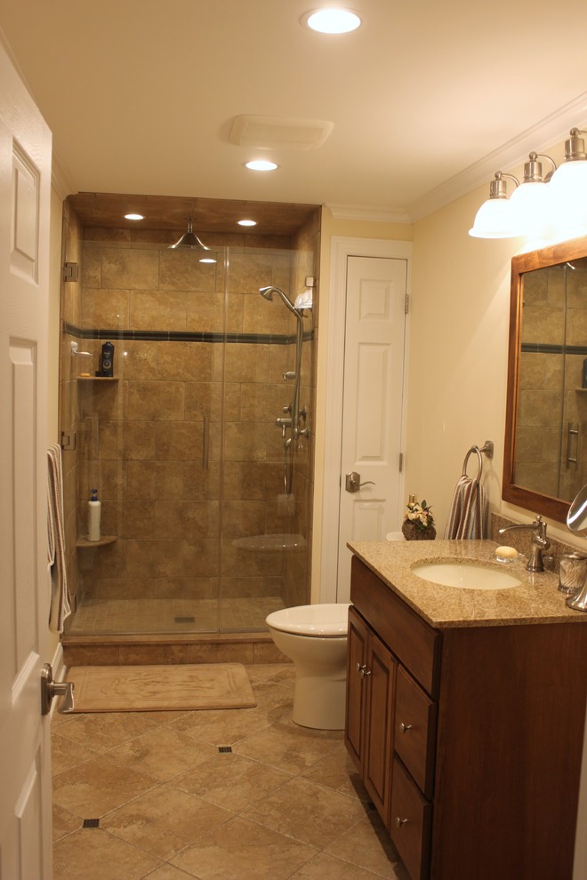 Mid-sized traditional 3/4 bathroom in Philadelphia with raised-panel cabinets, dark wood cabinets, an alcove shower, a two-piece toilet, ceramic tile, beige walls, ceramic floors, an undermount sink, granite benchtops, beige floor, a hinged shower door and beige tile.