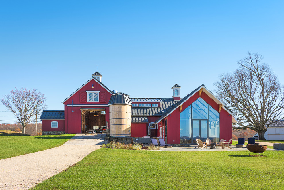 This is an example of an expansive country red house exterior in New York with wood siding and a metal roof.