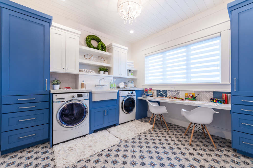 Photo of a mid-sized transitional utility room in Salt Lake City with a farmhouse sink, shaker cabinets, blue cabinets, quartz benchtops, ceramic floors, a side-by-side washer and dryer, white walls and multi-coloured floor.