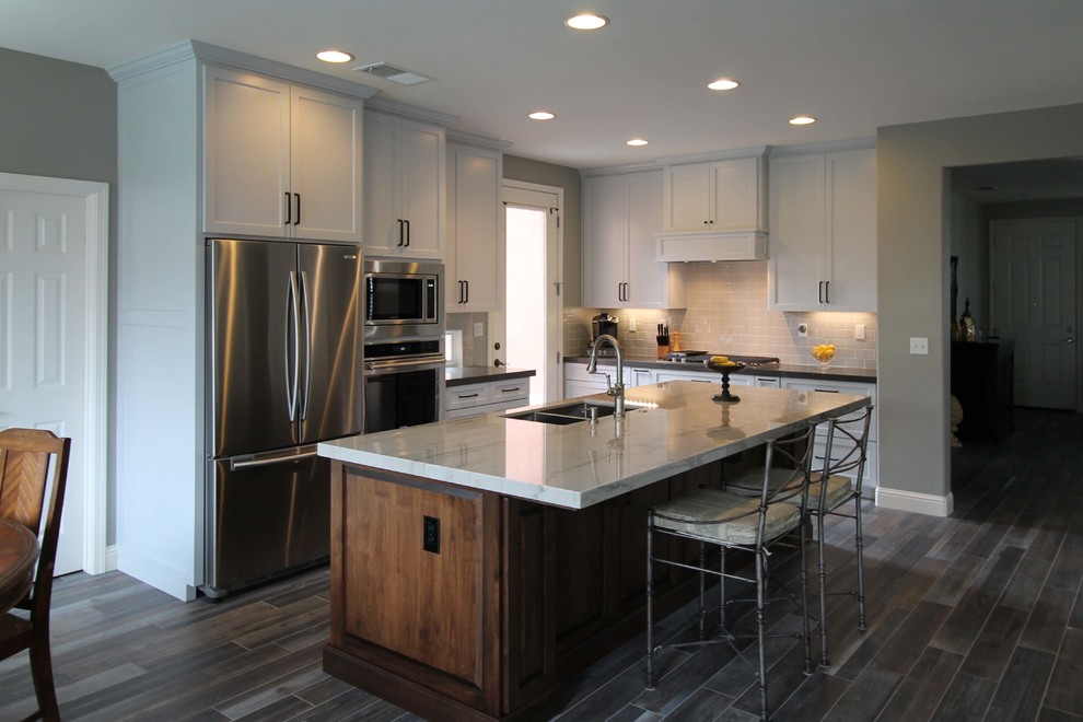 Inspiration for a mid-sized transitional l-shaped porcelain tile open concept kitchen remodel in Sacramento with an undermount sink, shaker cabinets, gray cabinets, quartzite countertops, gray backsplash, ceramic backsplash, stainless steel appliances and an island