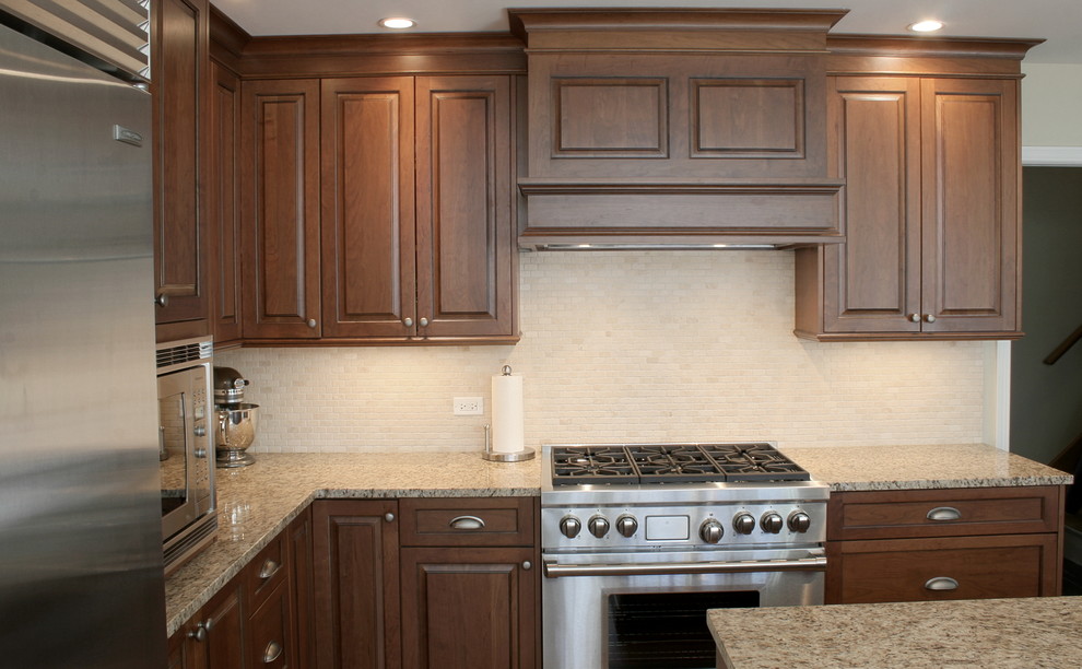 Example of a large transitional l-shaped dark wood floor eat-in kitchen design in Chicago with an undermount sink, raised-panel cabinets, medium tone wood cabinets, granite countertops, beige backsplash, subway tile backsplash, stainless steel appliances and an island