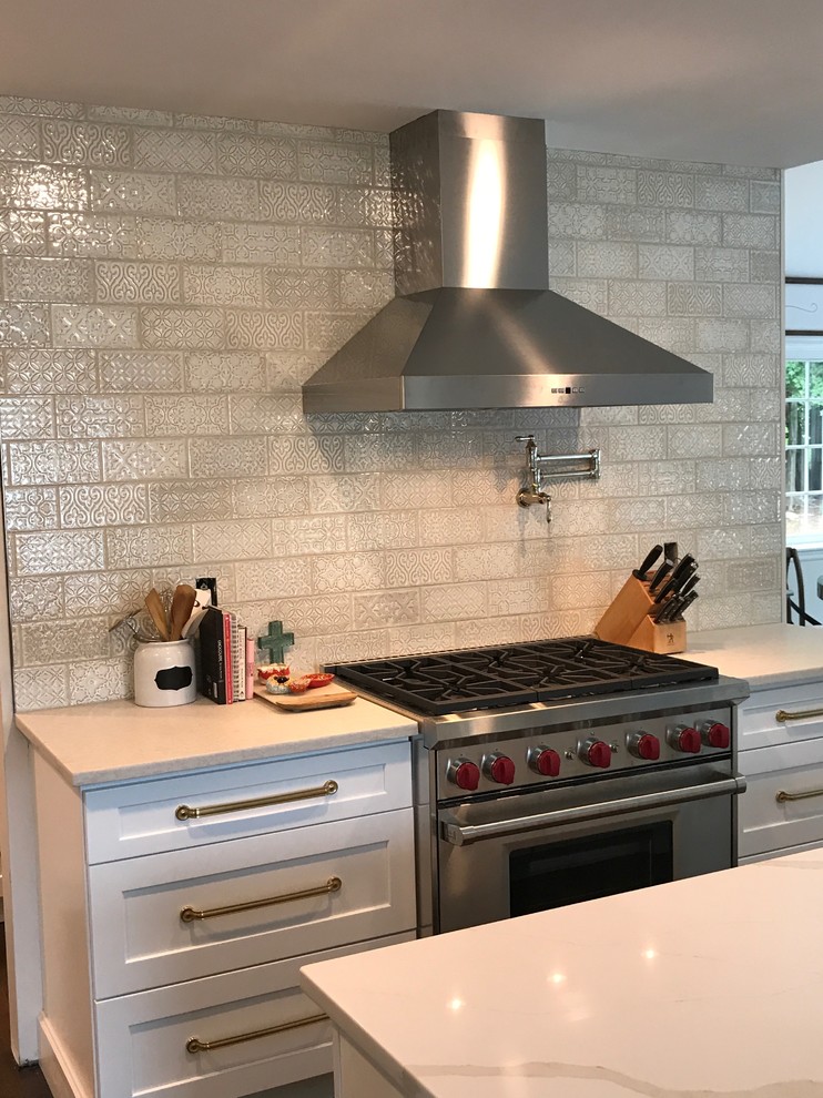 Photo of a mid-sized transitional single-wall eat-in kitchen in New York with shaker cabinets, white cabinets, quartz benchtops, beige splashback, ceramic splashback, stainless steel appliances, with island and white benchtop.