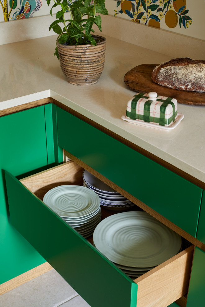 Design ideas for a contemporary l-shaped eat-in kitchen in London with green cabinets, solid surface benchtops, with island and beige benchtop.