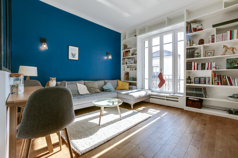 Photo of a scandinavian living room in Paris with light hardwood floors.